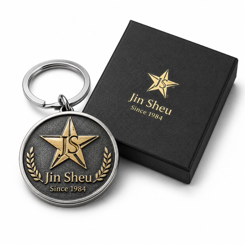 Custom round Jin Sheu star metal keychain with textured background next to premium black logo gift box.