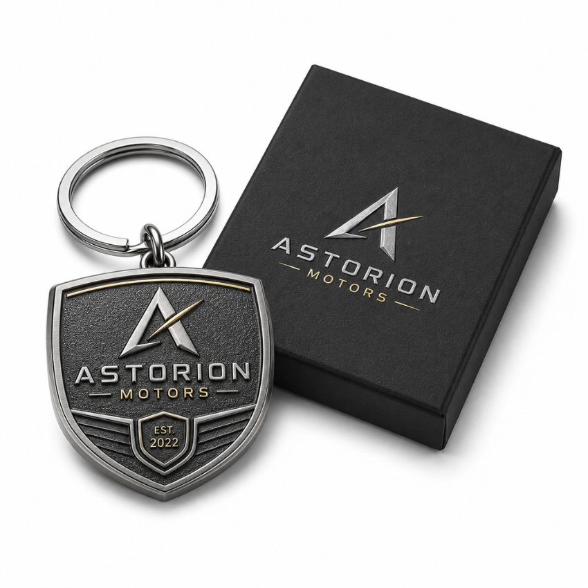 Custom Astorion Motors shield metal keychain featuring 3D antique finish beside a branded gift box.