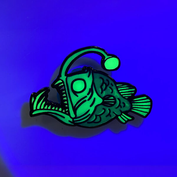 custom monkfish logo glow in the dark lapel pin close light