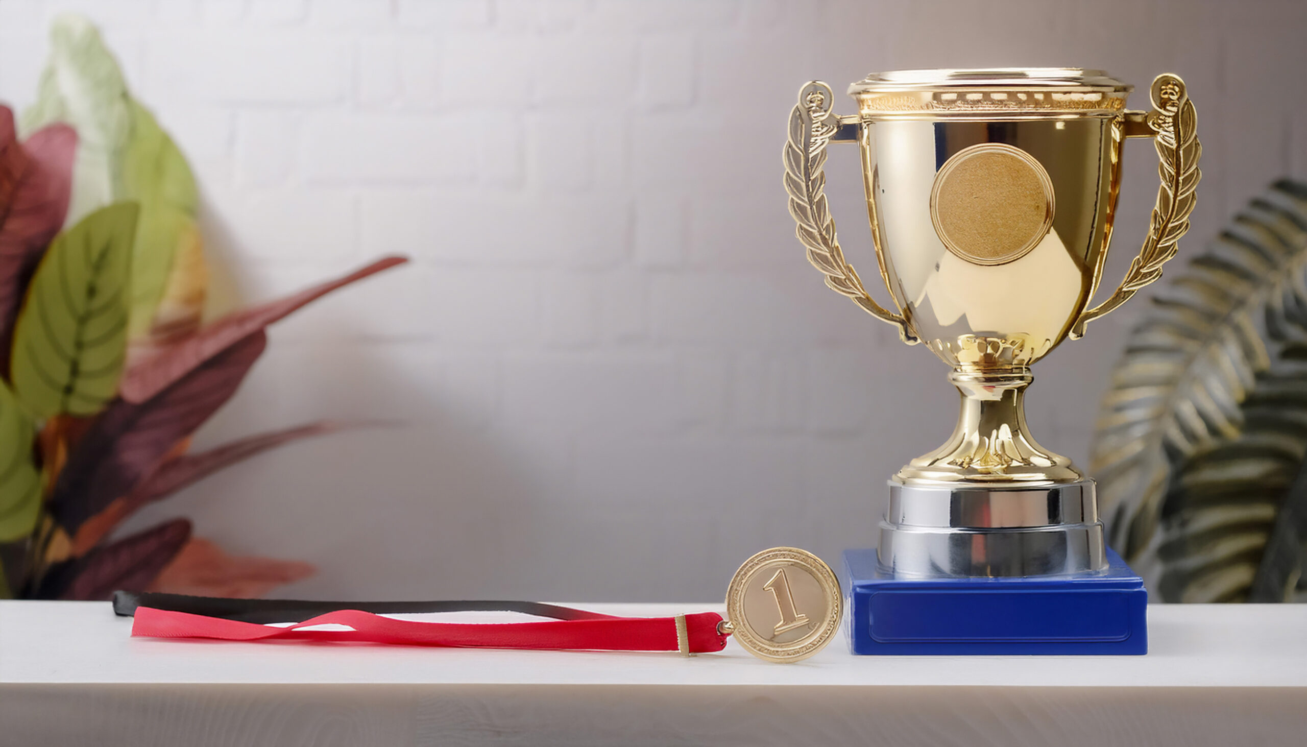 A medal and a trophy made with metal and gold plating.