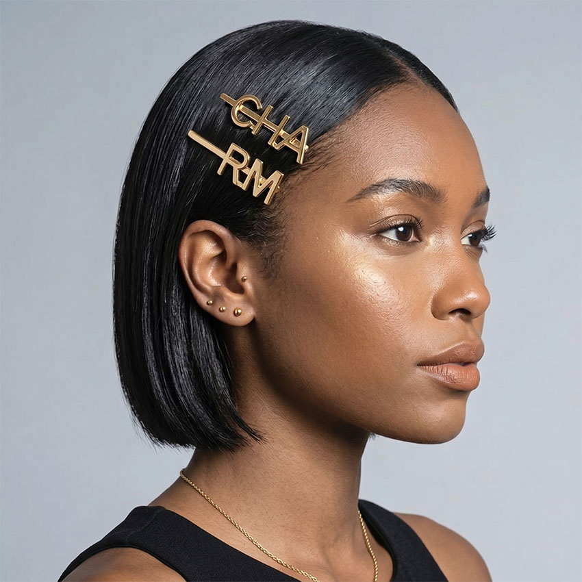 Model wearing custom gold letter hair pins spelling CHARM. Wholesale B2B hair jewelry manufacturer.