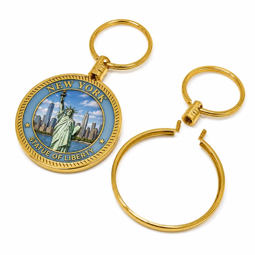 Gold coin bezel keychain with a detachable screw-top mechanism next to a New York Statue of Liberty challenge coin.