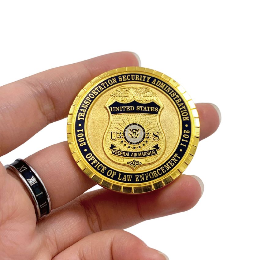 Person holding a gold plated agency challenge coin highlighting the detailed 3D die-cast texture.