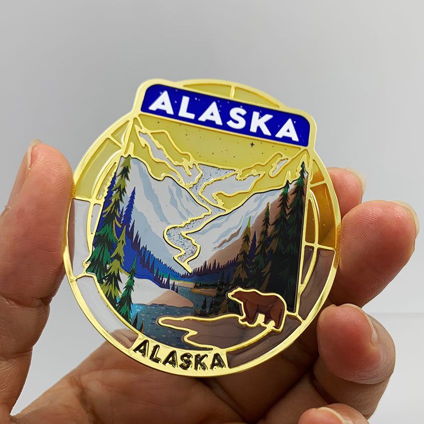 Handheld view of a custom Alaska transparent soft enamel bookmark showing stained-glass effect and UV printed graphics.