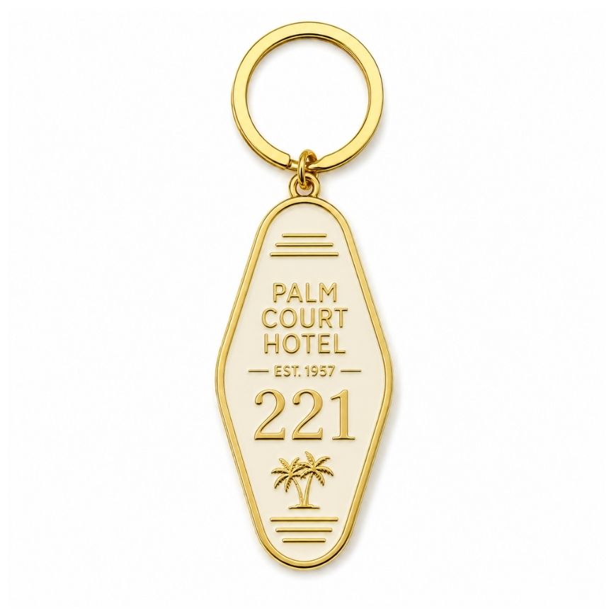 Custom off-white enamel motel key fob with gold palm tree graphic, designed for luxury hotel guest room keys.