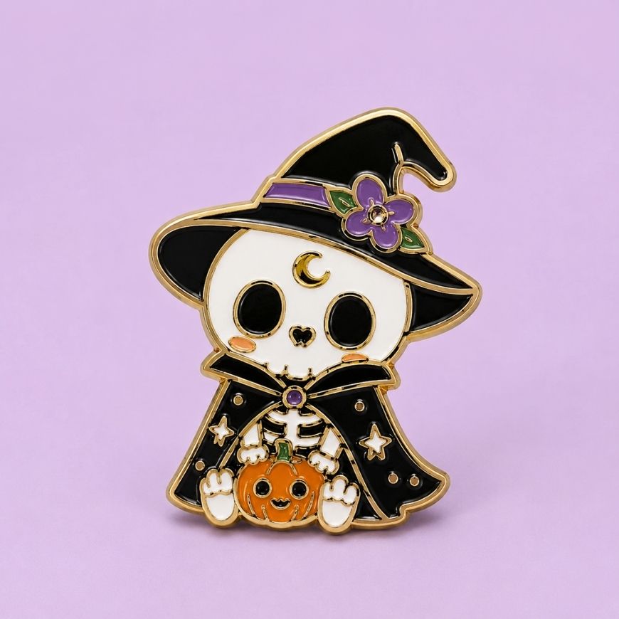 Cute skeleton witch holding pumpkin enamel pin, custom gold-plated metal accessory for Halloween merchandise.
